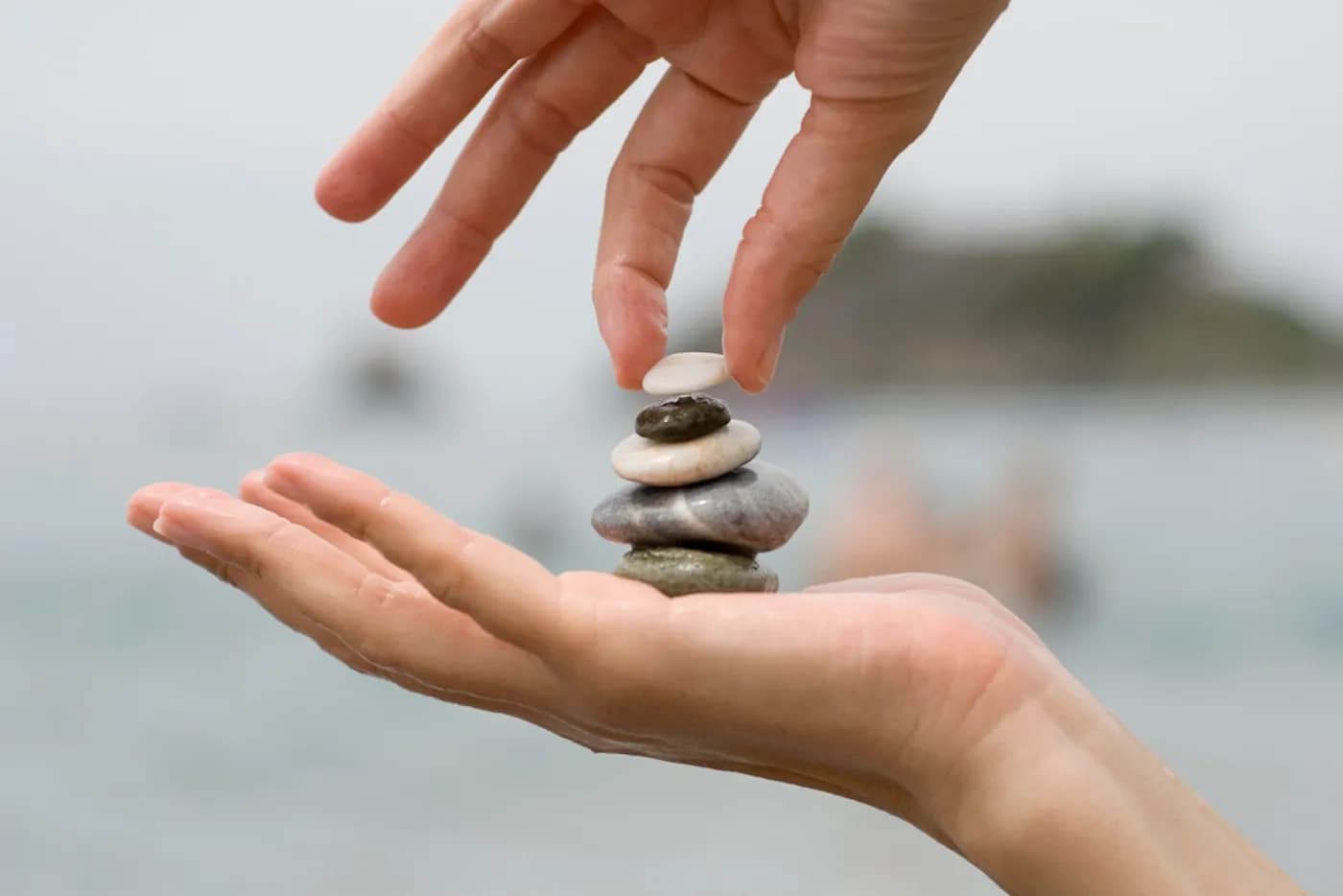 A hand placing a small stone on a stack